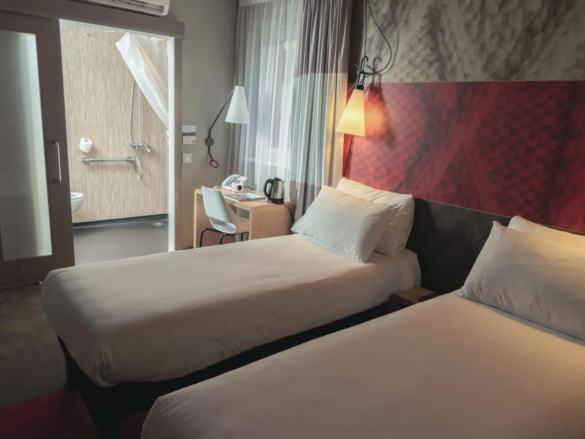 a hotel room with two beds and a desk at ibis Glasgow City Centre – Sauchiehall St in Glasgow