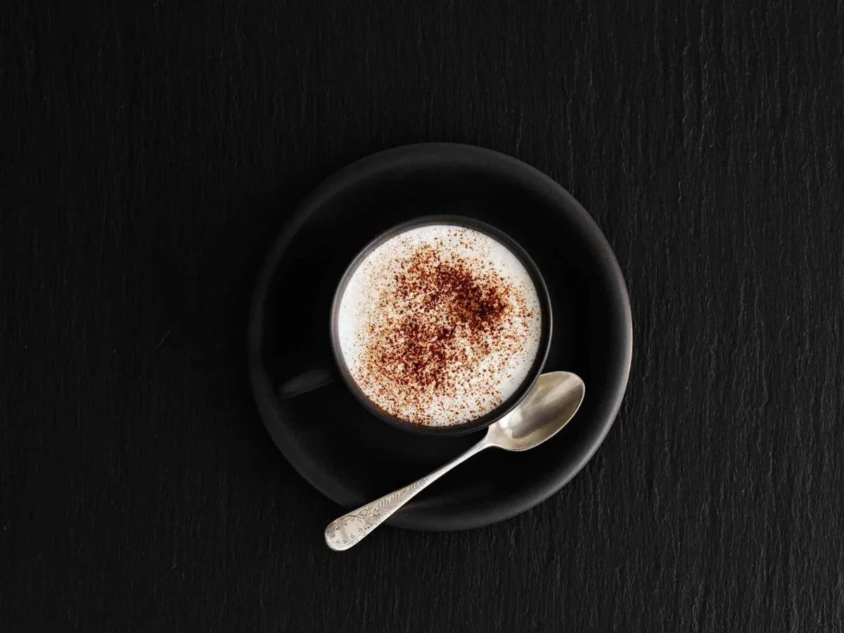 a black cup of coffee on a black plate with a spoon at ibis Glasgow City Centre – Sauchiehall St in Glasgow